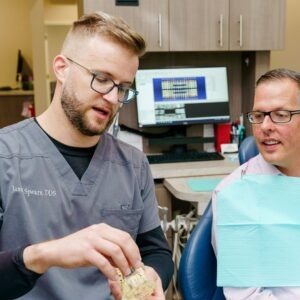 dentist demonstrating to a patient using a 3D tooth model 