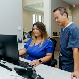 dentist looking over billing or scheduling at reception of dental office 
