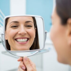 a person smiling while looking at a mirror with healthy-looking teeth and prominent smile.