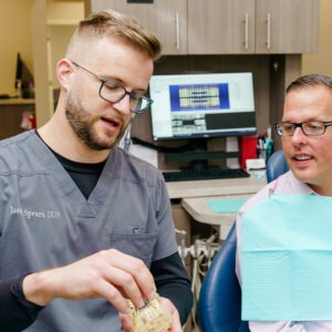 Dr. Jason Spears consulting with a patient using a dental model.